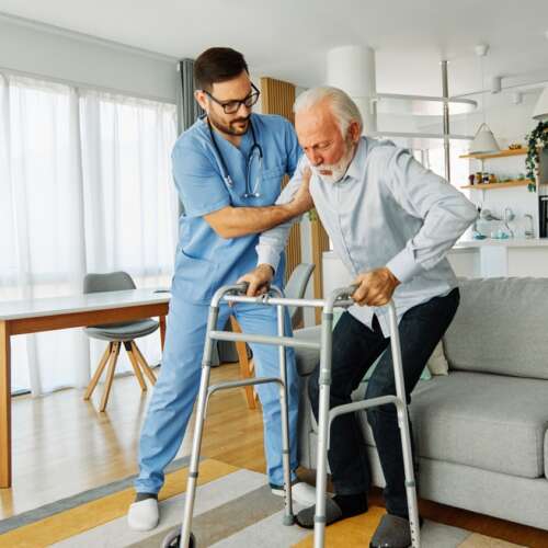 Compassionate Care. nurse helping elderly man walk