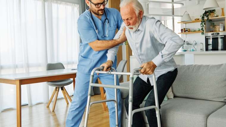 Compassionate Care. nurse helping elderly man walk